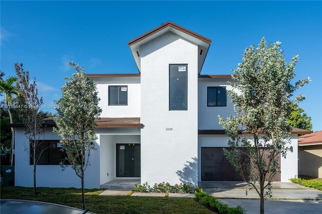 contemporary house with driveway, an attached garage, and stucco siding