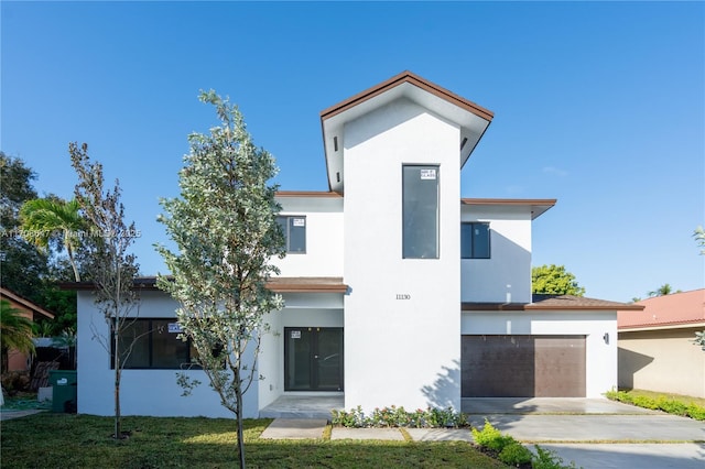 contemporary house featuring a garage, driveway, and stucco siding