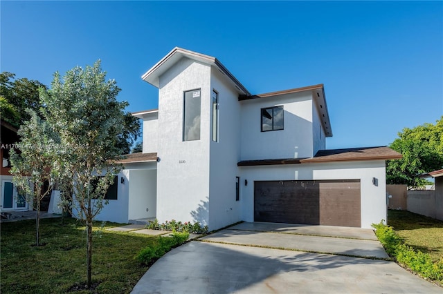 view of front facade with an attached garage, driveway, a front lawn, and stucco siding