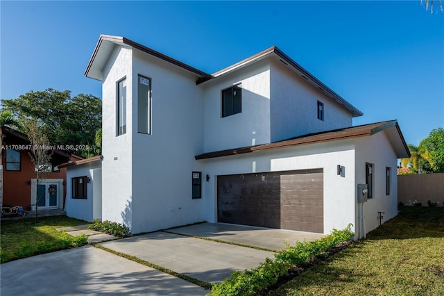 rear view of house featuring an attached garage, a yard, concrete driveway, and stucco siding