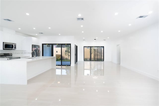 kitchen with stainless steel appliances, visible vents, open floor plan, white cabinets, and a sink