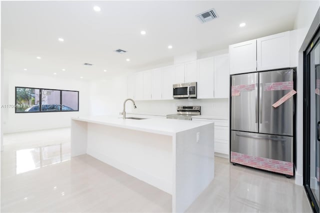 kitchen with stainless steel appliances, a sink, visible vents, and white cabinetry