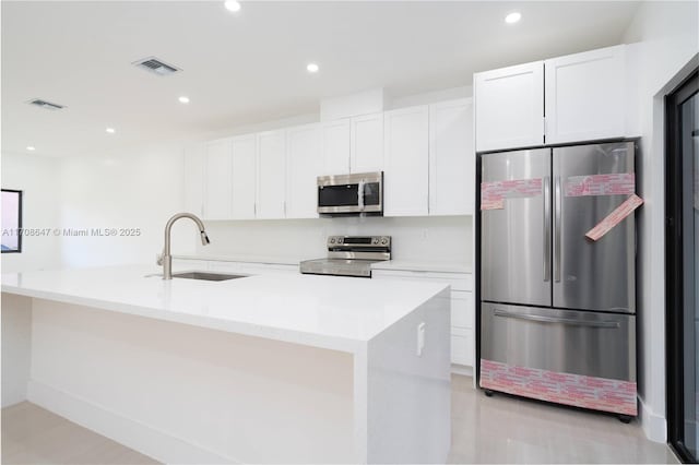 kitchen featuring appliances with stainless steel finishes, a sink, visible vents, and white cabinets