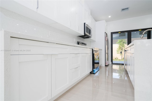 kitchen with stainless steel appliances, recessed lighting, white cabinets, and visible vents