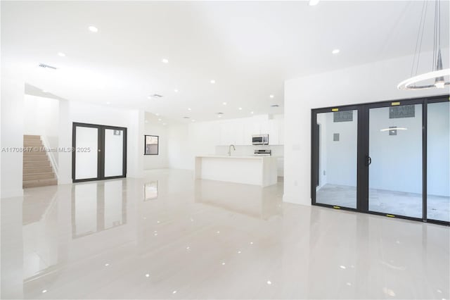 unfurnished living room with recessed lighting, stairs, visible vents, and french doors