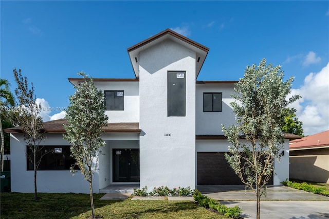 contemporary house with driveway, an attached garage, and stucco siding