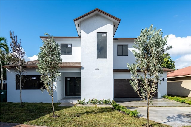 modern home featuring driveway, a front yard, an attached garage, and stucco siding