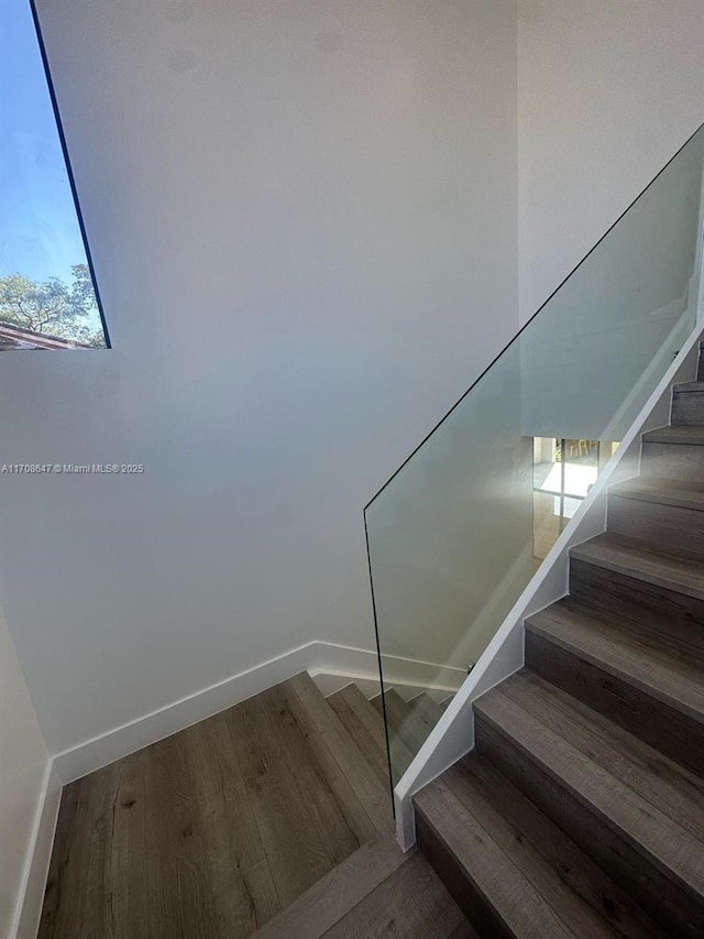 staircase featuring wood finished floors and baseboards