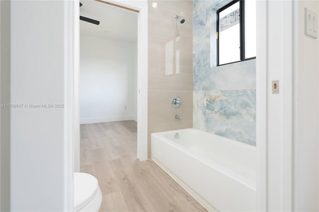 bathroom with shower / bath combination, wood finished floors, toilet, and baseboards