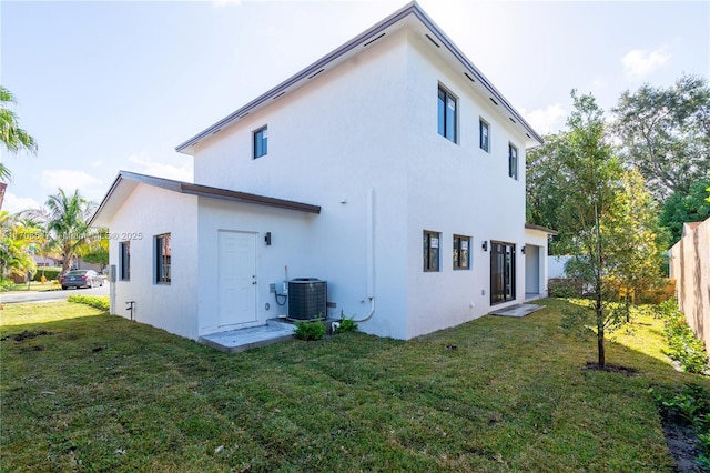 back of house with a lawn, fence, cooling unit, and stucco siding