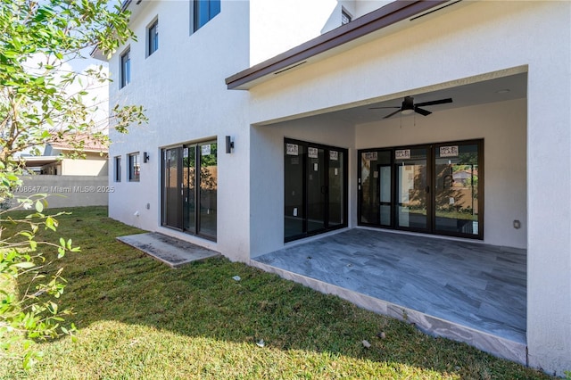 back of property featuring stucco siding, ceiling fan, a patio area, and a yard