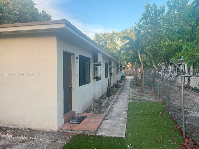 view of property exterior with stucco siding and fence