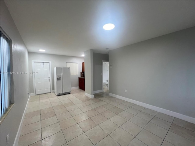 empty room featuring baseboards and light tile patterned floors