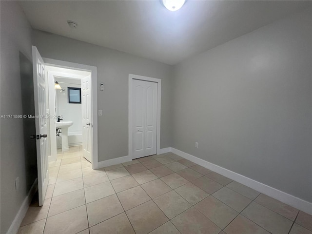 unfurnished bedroom featuring light tile patterned flooring, baseboards, and a closet