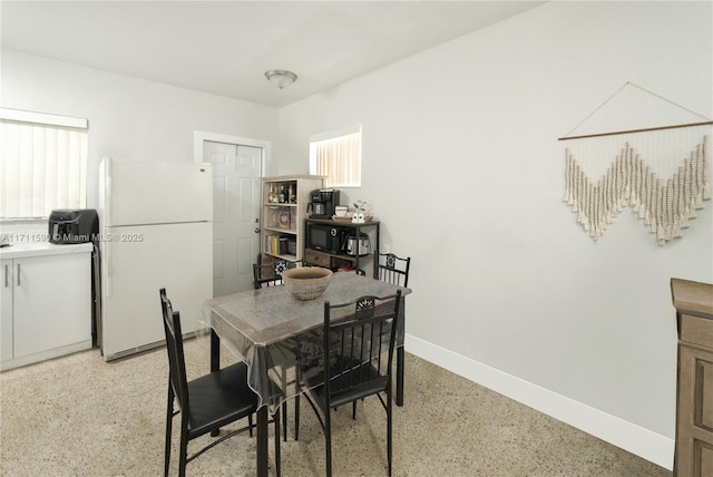 dining room featuring baseboards and light speckled floor
