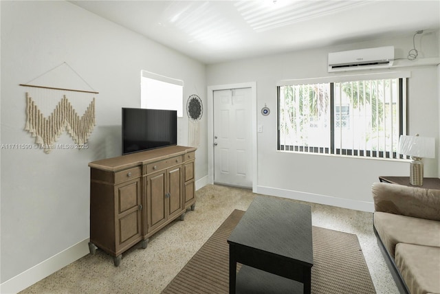 living room featuring a wall mounted air conditioner, baseboards, and light speckled floor