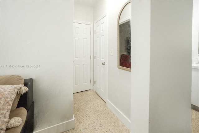 corridor with baseboards and speckled floor