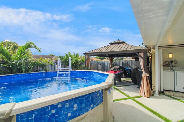 view of pool featuring a gazebo and washer / dryer