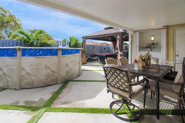 view of patio / terrace with separate washer and dryer, a fenced in pool, and a gazebo