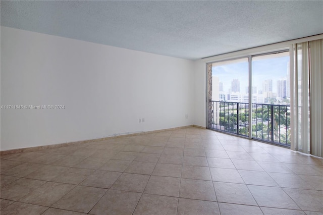 unfurnished room with a wall of windows, light tile patterned floors, and a textured ceiling