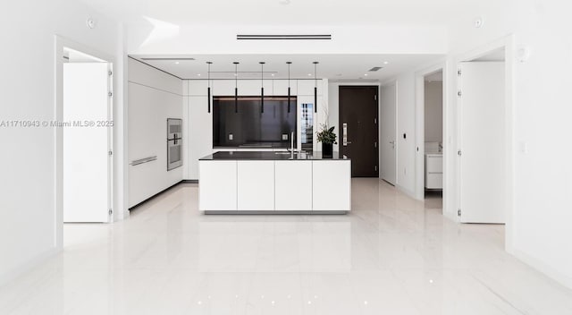 kitchen with white cabinets, refrigerator, hanging light fixtures, and sink