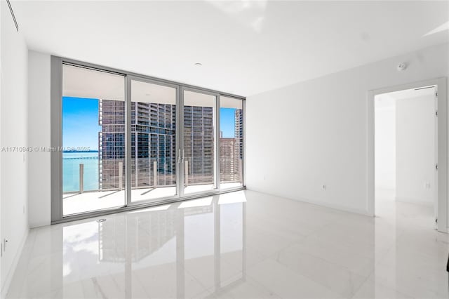 tiled spare room with floor to ceiling windows and a water view