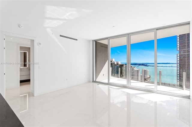 tiled spare room with floor to ceiling windows and a water view