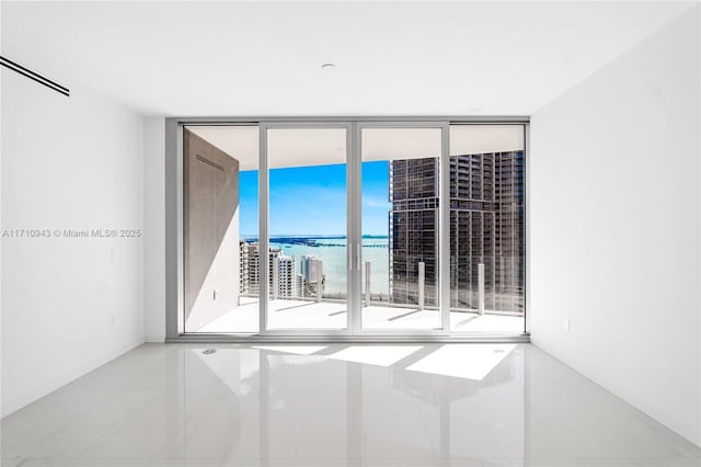 empty room with expansive windows, a wealth of natural light, a water view, and light tile patterned floors