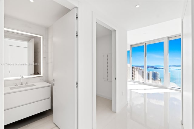 bathroom with vanity, a water view, and a wall of windows