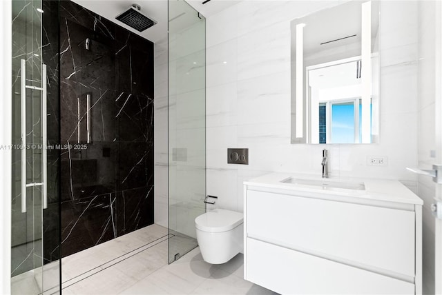 bathroom with tiled shower, vanity, tile walls, and toilet