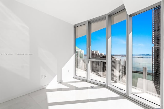 unfurnished room with a water view, expansive windows, and light tile patterned floors