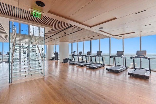 exercise room with expansive windows, a water view, wood-type flooring, and wood ceiling