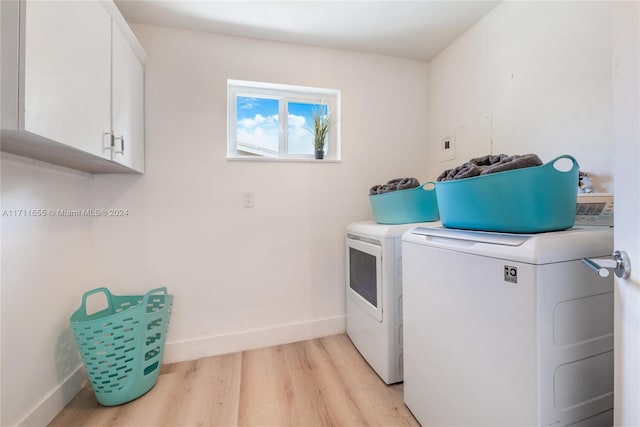 washroom with light hardwood / wood-style floors, cabinets, and separate washer and dryer