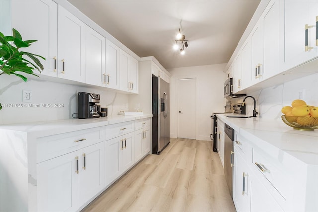 kitchen with tasteful backsplash, light stone counters, stainless steel appliances, light hardwood / wood-style flooring, and white cabinetry