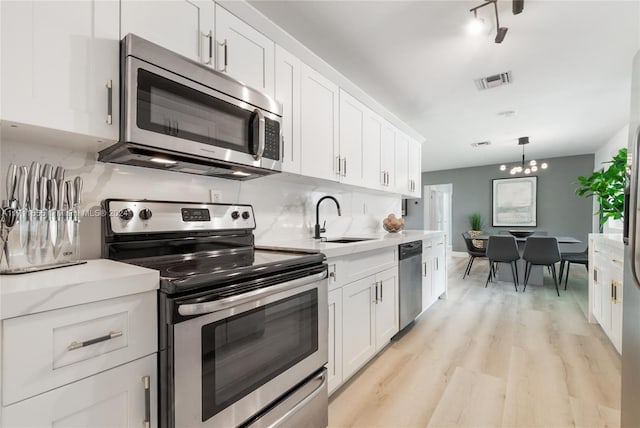 kitchen with sink, white cabinets, light hardwood / wood-style flooring, and appliances with stainless steel finishes