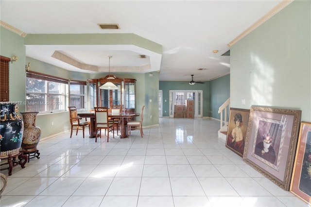 dining space with a raised ceiling, ceiling fan, light tile patterned floors, and ornamental molding