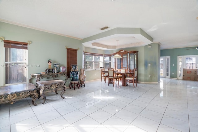 tiled dining area with ornamental molding, a raised ceiling, ceiling fan, and a healthy amount of sunlight