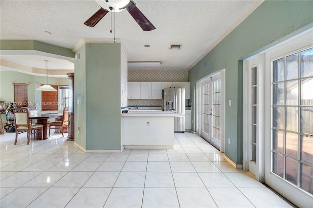 kitchen with kitchen peninsula, ceiling fan, a textured ceiling, white cabinetry, and stainless steel fridge with ice dispenser