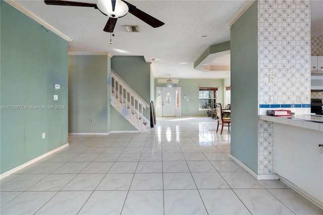 interior space with ceiling fan, light tile patterned floors, a textured ceiling, and ornamental molding