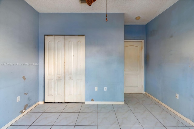 unfurnished bedroom featuring a closet, light tile patterned flooring, and a textured ceiling