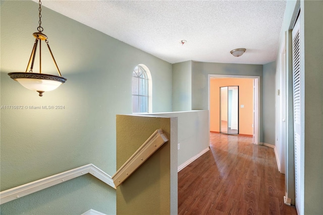 hall featuring wood-type flooring and a textured ceiling