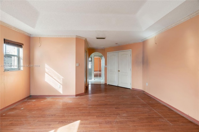 unfurnished room with wood-type flooring, a textured ceiling, and ornamental molding