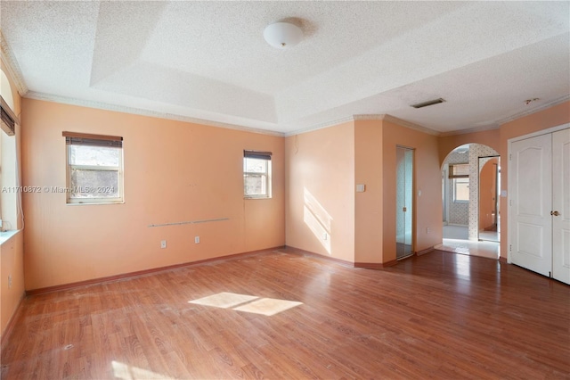 unfurnished room with plenty of natural light, crown molding, wood-type flooring, and a textured ceiling