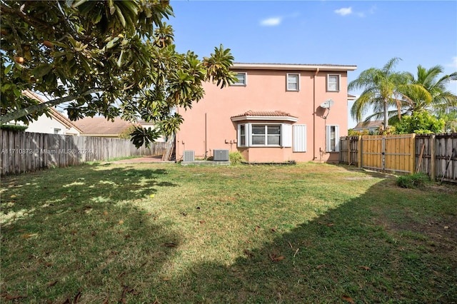 rear view of property with cooling unit and a yard