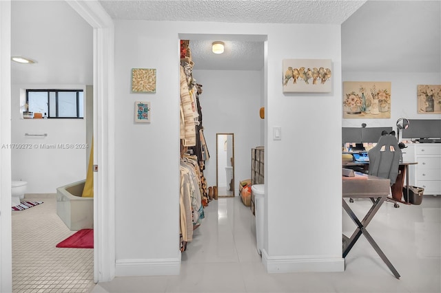 hallway with light tile patterned floors and a textured ceiling