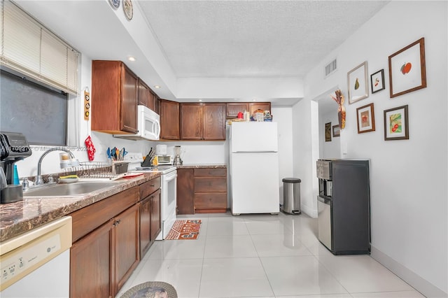 kitchen featuring a textured ceiling, white appliances, light tile patterned floors, and sink