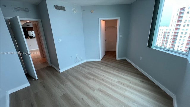 unfurnished bedroom featuring light hardwood / wood-style floors, a spacious closet, and a closet