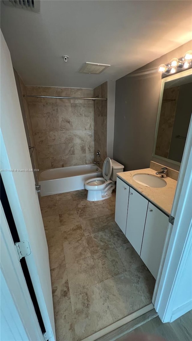 full bathroom featuring tiled shower / bath combo, toilet, and vanity