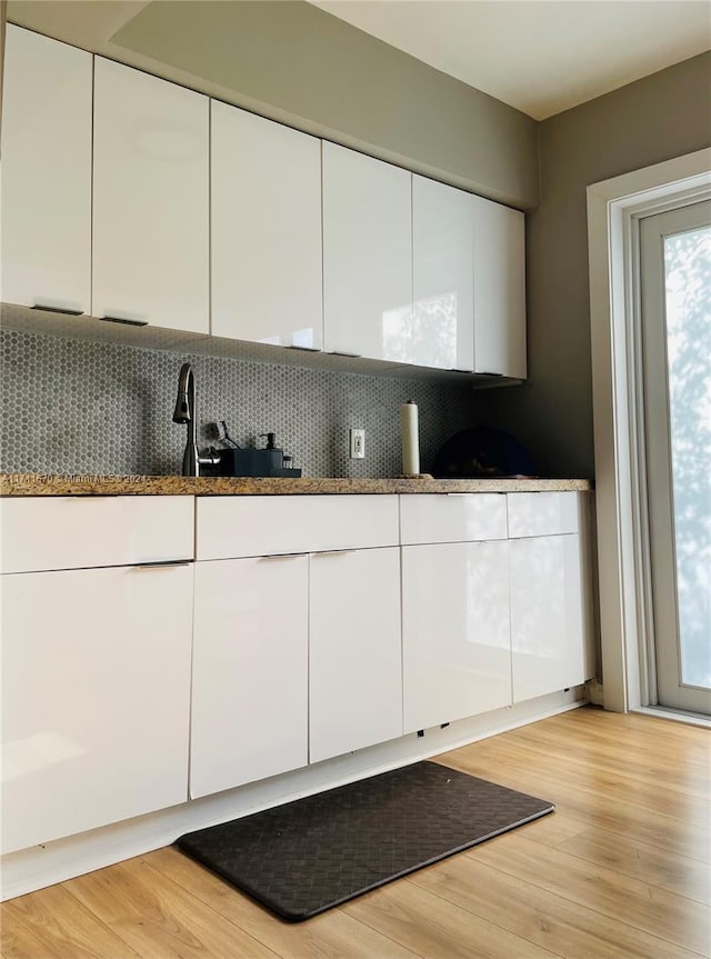 kitchen with white cabinets, light wood-type flooring, and sink