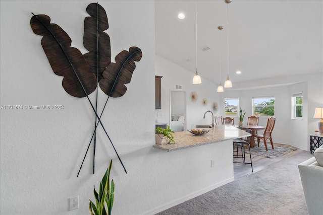 kitchen with light carpet, light stone countertops, sink, hanging light fixtures, and lofted ceiling